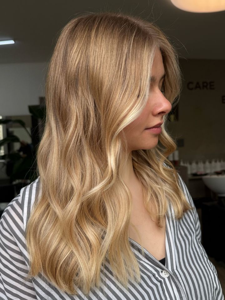 Cheveux mi-longs blonds et ondulés, vus de profil